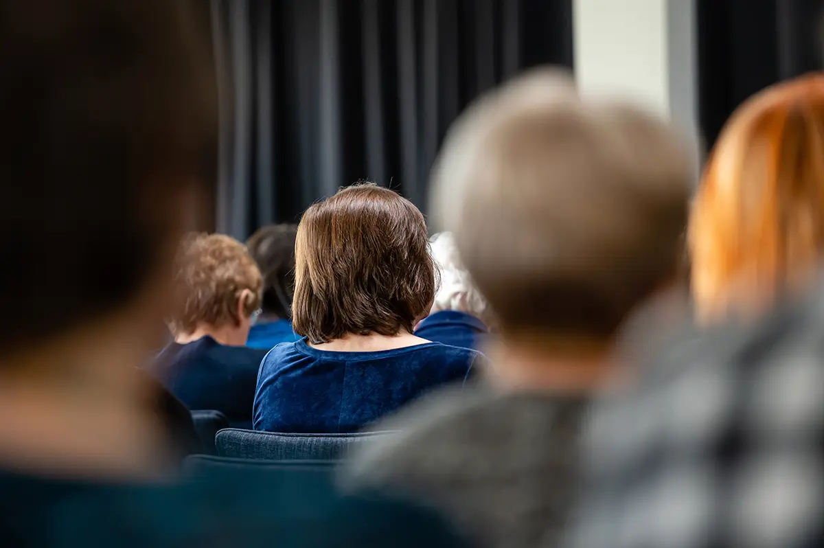 Zuschauer, die bei einer öffentlichen Beteiligungs- oder Interessensveranstaltung sitzen, von hinten gesehen